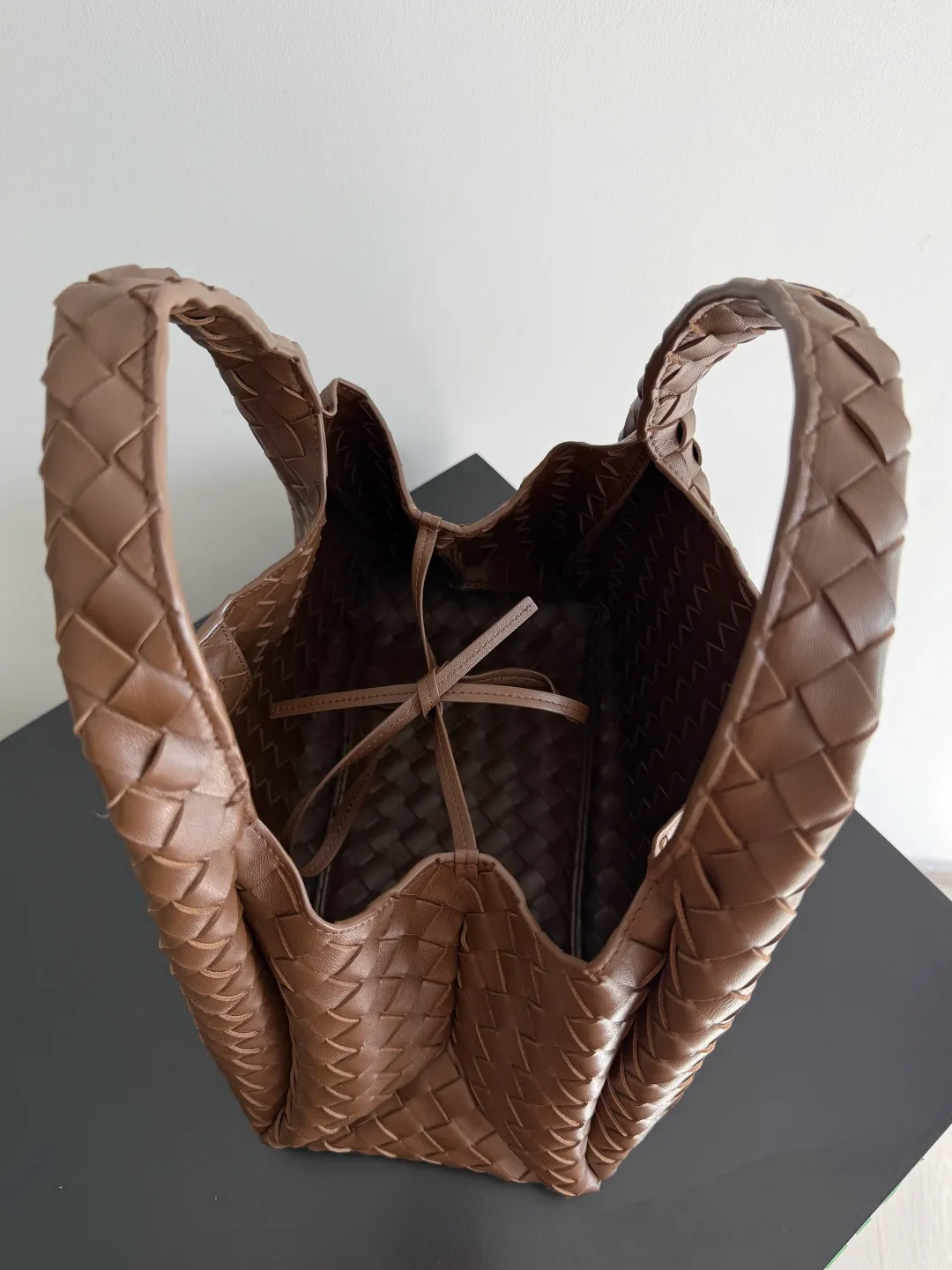 Batch 2160 new products are coming! BOTTEGA VENETA Bottega Veneta's 2025 new Campana shoulder bag is on the market~ First of all, I would like to praise the weight of this bag. As a not too small bag, it is very light for daily use. For people like me who need to carry a lot of belongings when going out, this advantage is great, and it greatly reduces the burden of traveling. 🛍️The shape is a bit like a combination of parachute and jodie. The blunt triangle shape is cute and honest. Carrying it on your back when going shopping is a good mood accelerator. The handles and body of the bag are both classic weaves. A tie is added to the original open design. If it is not tied up, the bag will look like a small vegetable basket when carried. Style number: 844249 Size: 33*20*16.5cm